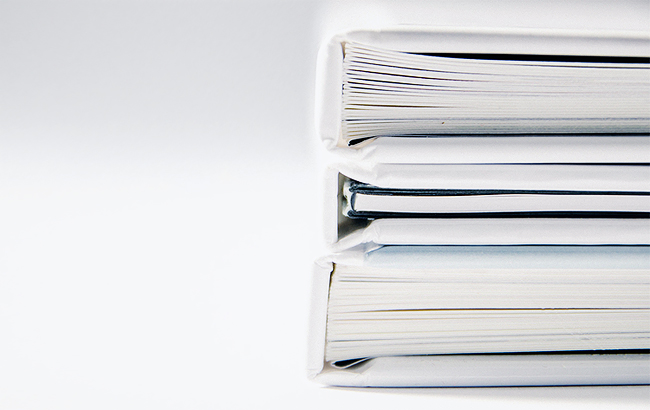 Stack of binders filled with documents against a white backdrop